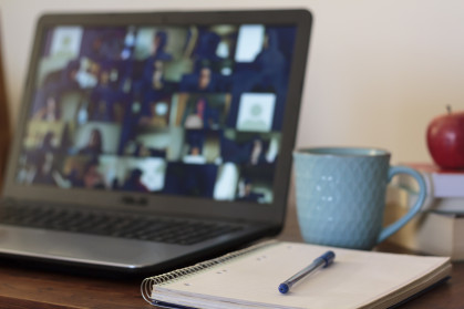 A laptop is open on a table to an online meeting.