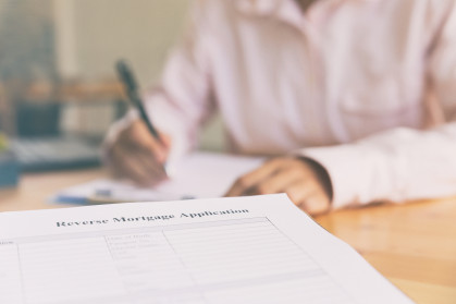 Hand fill out reverse mortgage loan application on a clipboard.