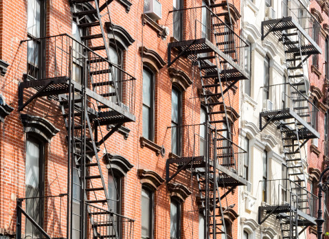 New York City style apartment buildings exterior view with windows and fire escapes