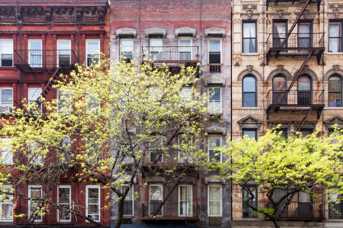 a row of new york city apartments with trees in front.